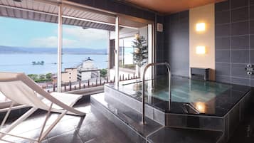 Un espace spa comprenant un jacuzzi, une vue sur la mer et un coin salon agrémenté d’une rambarde.
