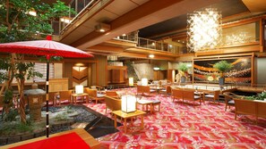 A hotel lobby with a traditional Japanese design, featuring tatami mat flooring, wooden furniture, and a koi pond.