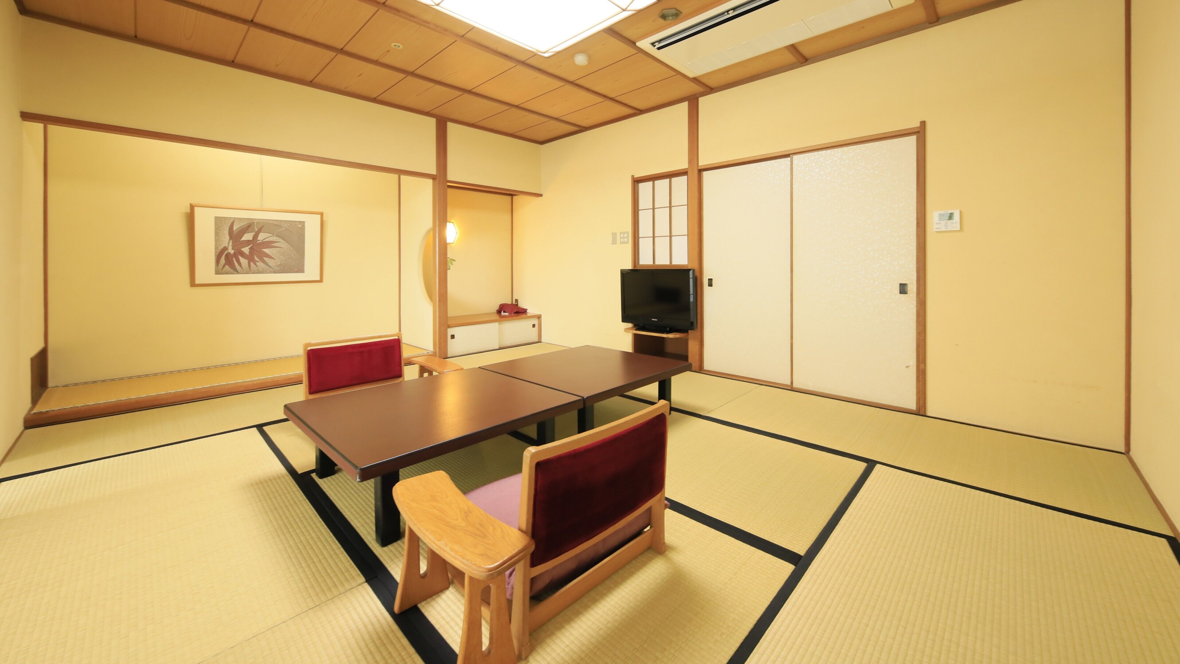 Una habitación japonesa tradicional con suelo de tatami, una mesa baja y un televisor.