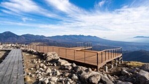 A wooden viewing platform with a metal railing, overlooking a mountainous landscape. - Hamanoyu (Suwa)
