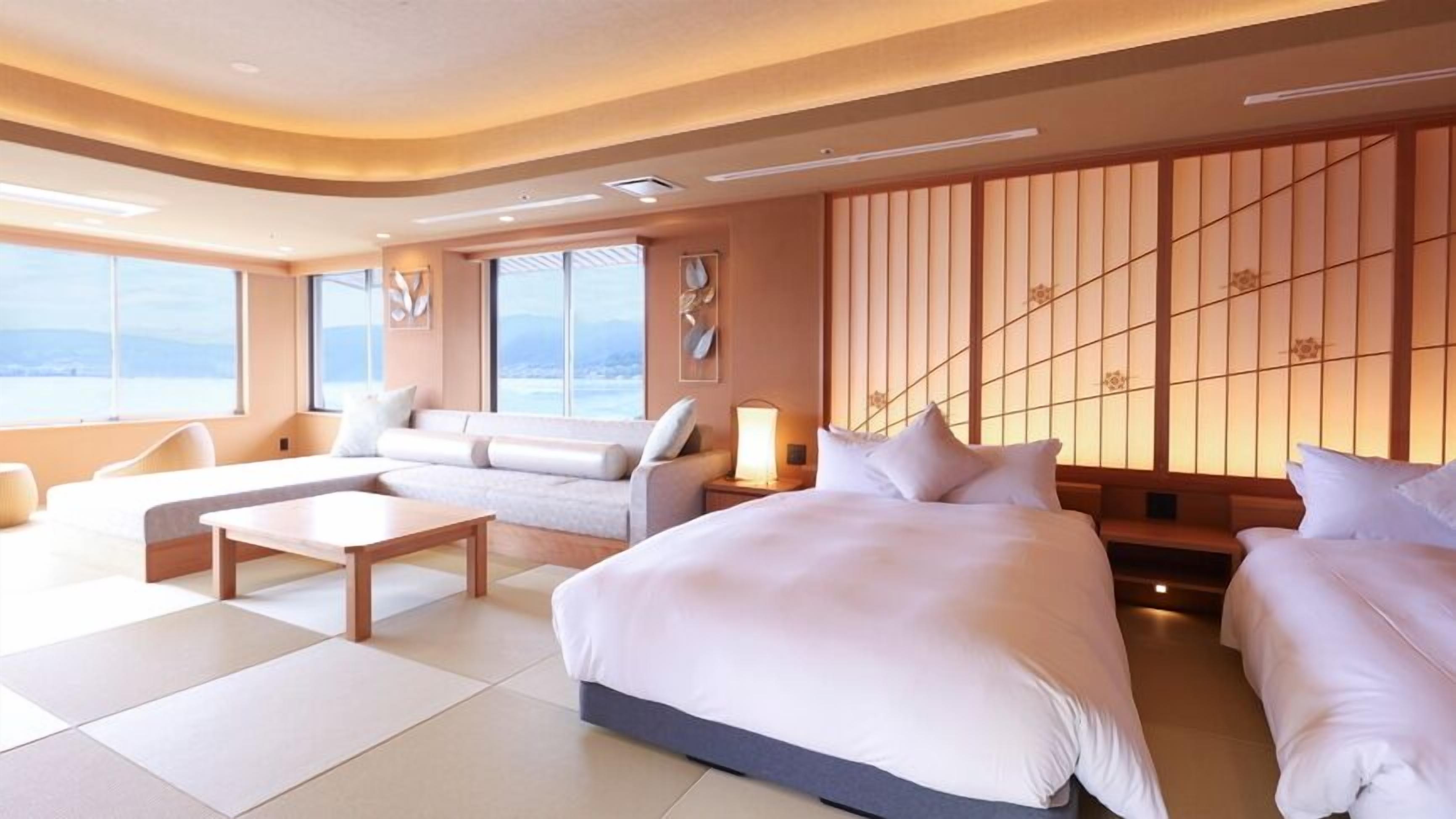 Habitación de hotel moderna con una cama grande, un sofá, una mesa de centro y vistas al exterior.