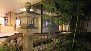 A traditional Japanese-style building with a stone lantern and a bamboo fence.