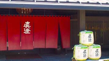 A building entrance with a red curtain and Chinese characters, and four stacked packages labeled 'Masumi.'