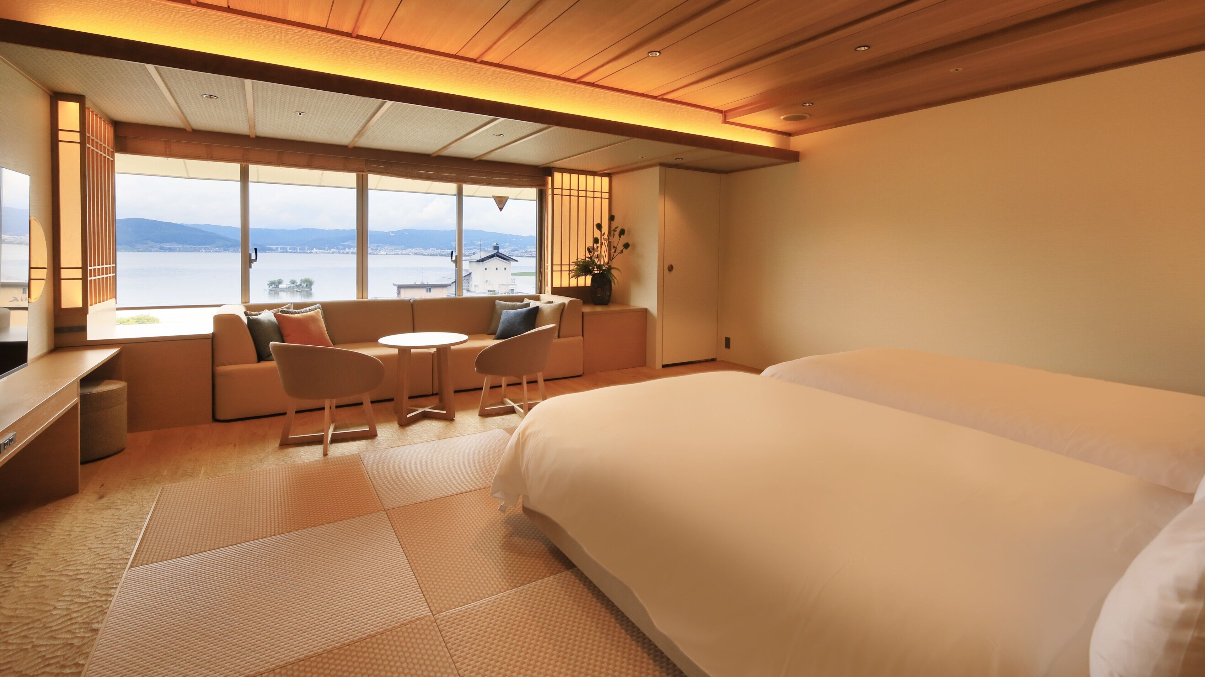 Habitación de hotel con una cama grande, zona de estar con una mesa y vista al mar.