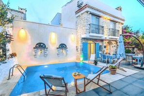 A poolside area with a stone building, outdoor seating, and a pool. - Alacati Asmali Konak Otel (Çeşme)