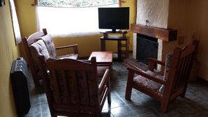 Ein Wohnzimmer mit Fernseher, Kamin und zwei Holzstühlen.