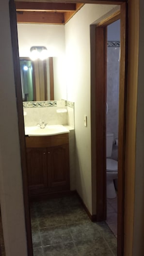 A narrow hallway leading to a bathroom with a sink, mirror, and toilet. - La Colella (San Martín de los Andes)