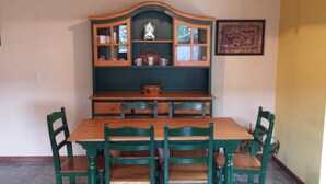 Ein Esstisch mit sechs Stühlen, ein Holzschrank darüber und ein gerahmtes Bild an der Wand.
