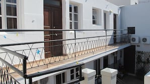 A balcony with a metal railing, a wooden floor, and air conditioning units on the building's exterior. - Lindos Marianthi Studios (Rhodes)