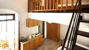 A compact kitchen with wooden cabinets, a sink, and a small countertop. - Lindos Marianthi Studios (Rhodes)
