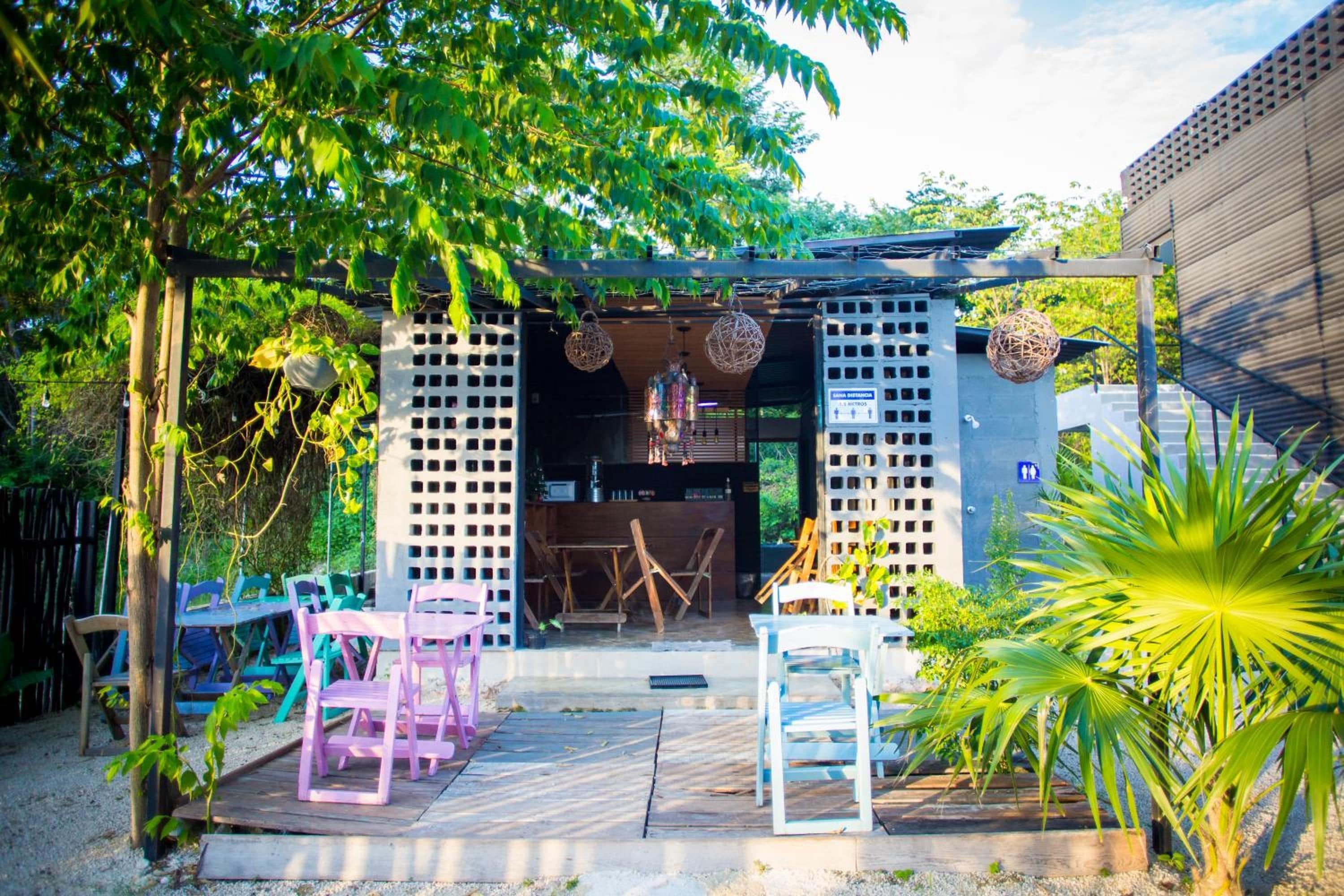 An outdoor patio area with a covered seating area, tables, chairs, and a view of the surrounding greenery.