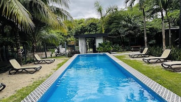 Una piscina al aire libre, sillones reclinables de piscina