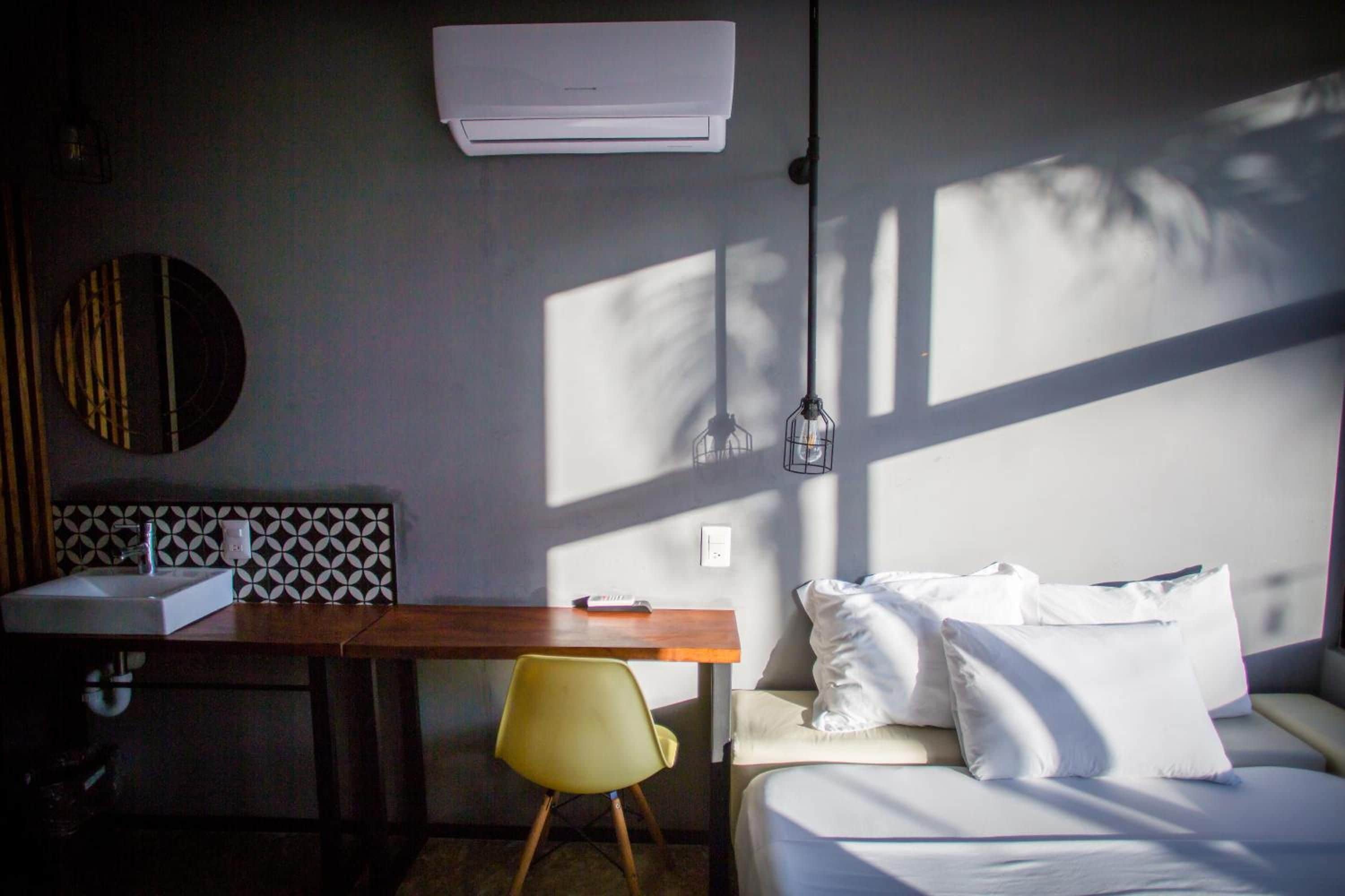 Une chambre comprenant un lit, un bureau, une chaise, un lavabo et un climatiseur.