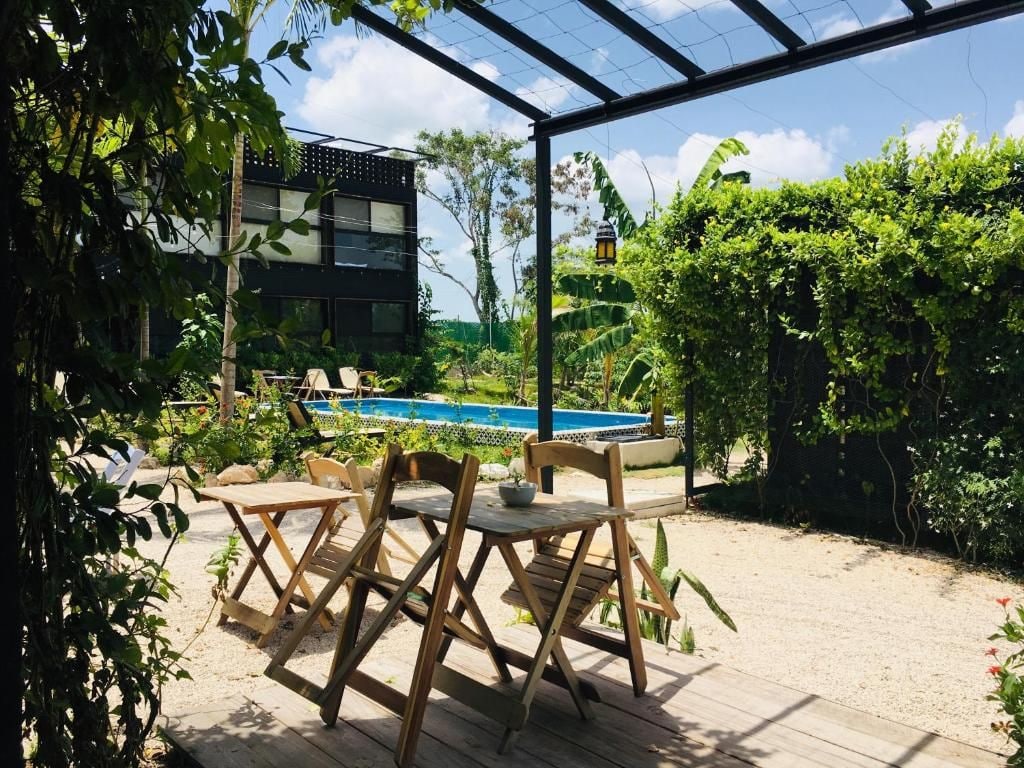 An outdoor seating area with a pool, surrounded by greenery and a modern building.