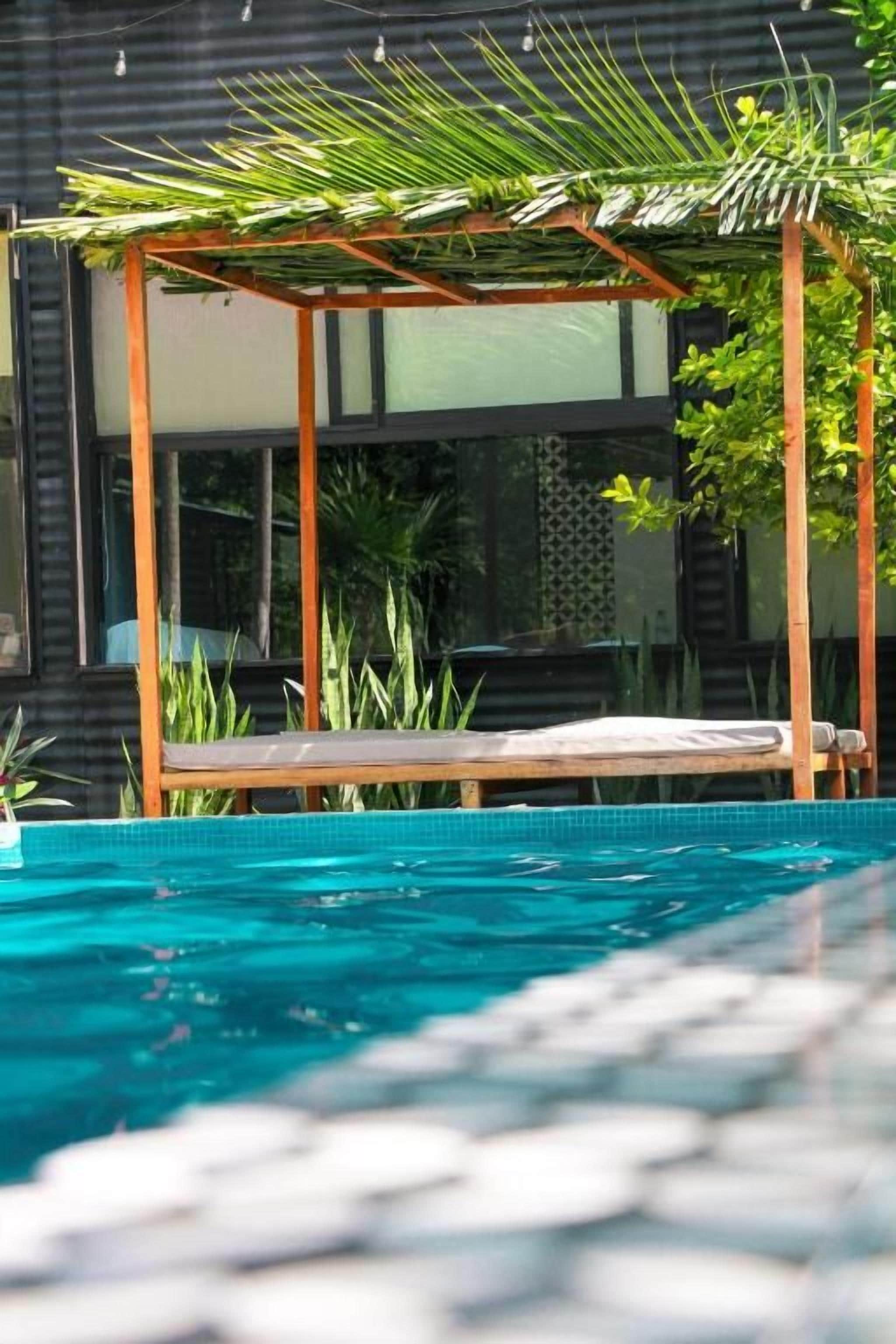 Een zwembad met houten terras en een pergola.