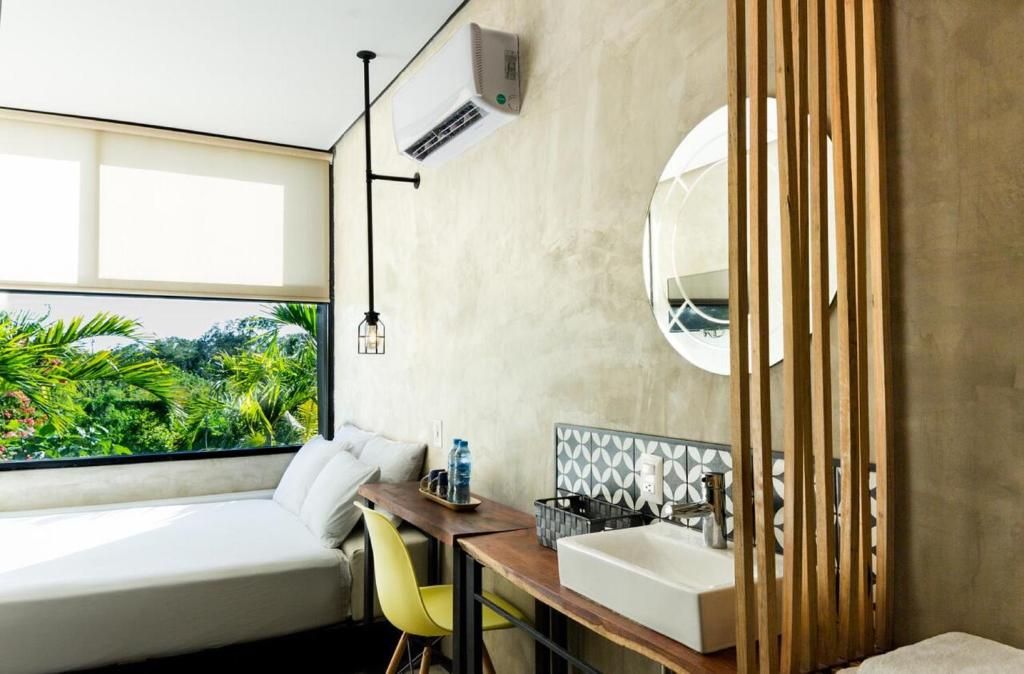 A modern bathroom with a large window, a wooden partition, a white sink, and a mirror.