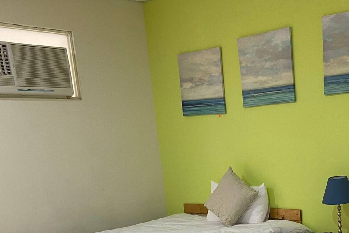 A room with a bed, a nightstand, a lamp, and three paintings of the sea on the wall.