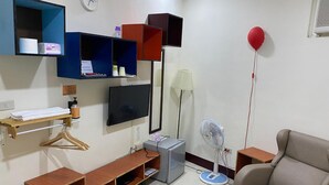 A living room with a TV, shelves, a sofa, a fan, and a red balloon. - Luyu Homestay (Lukang)