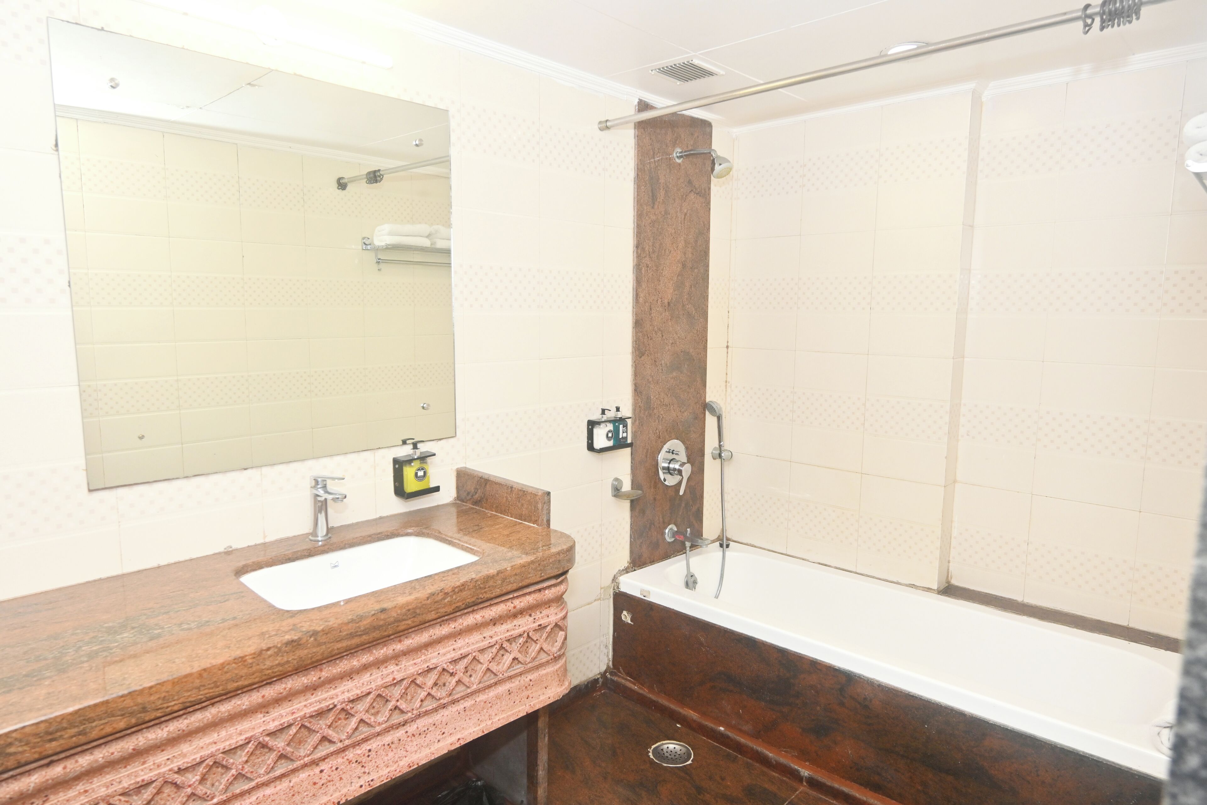 A bathroom with a wooden vanity, a large mirror, a bathtub, and a shower.
