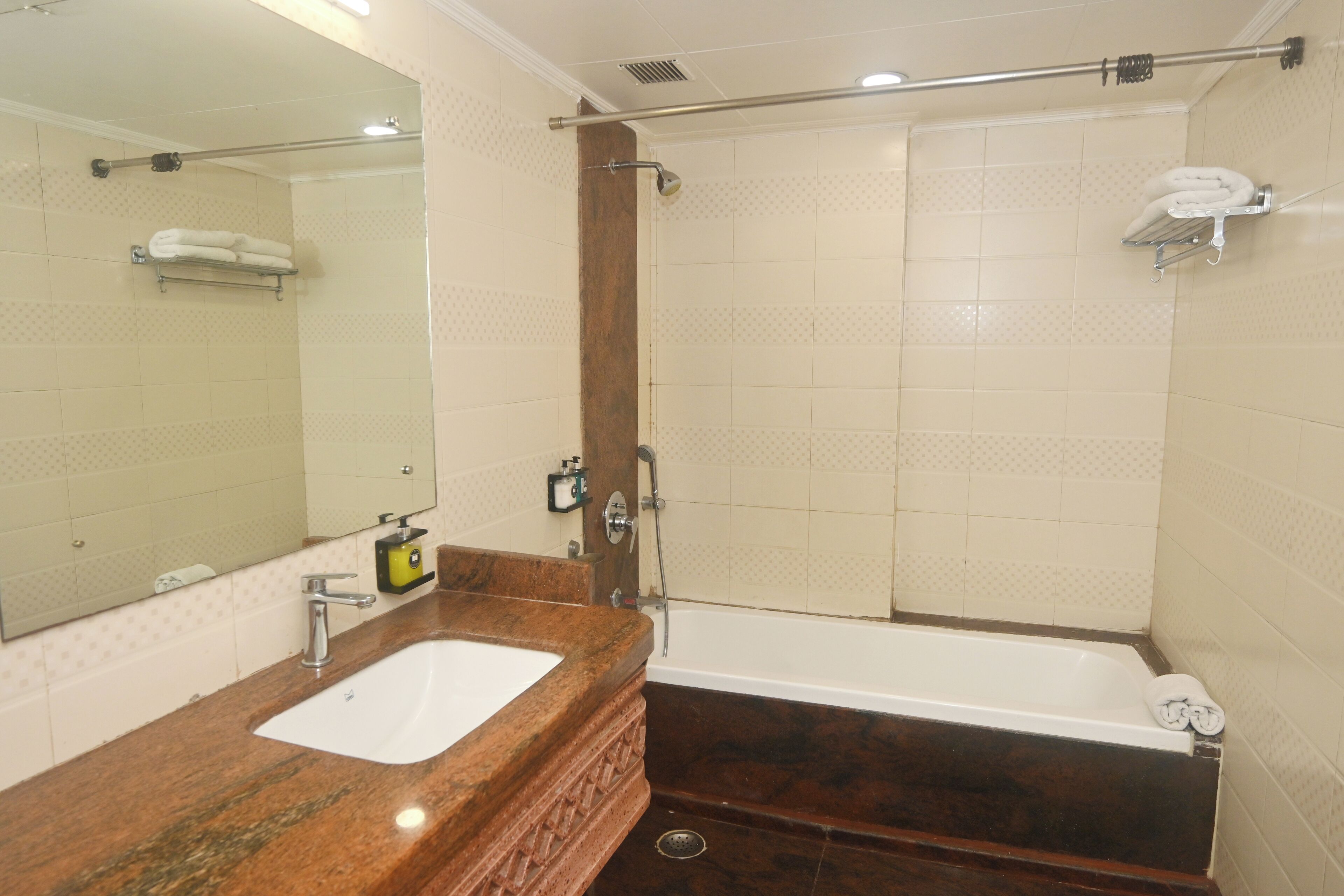 Un baño con lavamanos de mármol, un espejo grande, una bañera y una zona de ducha.