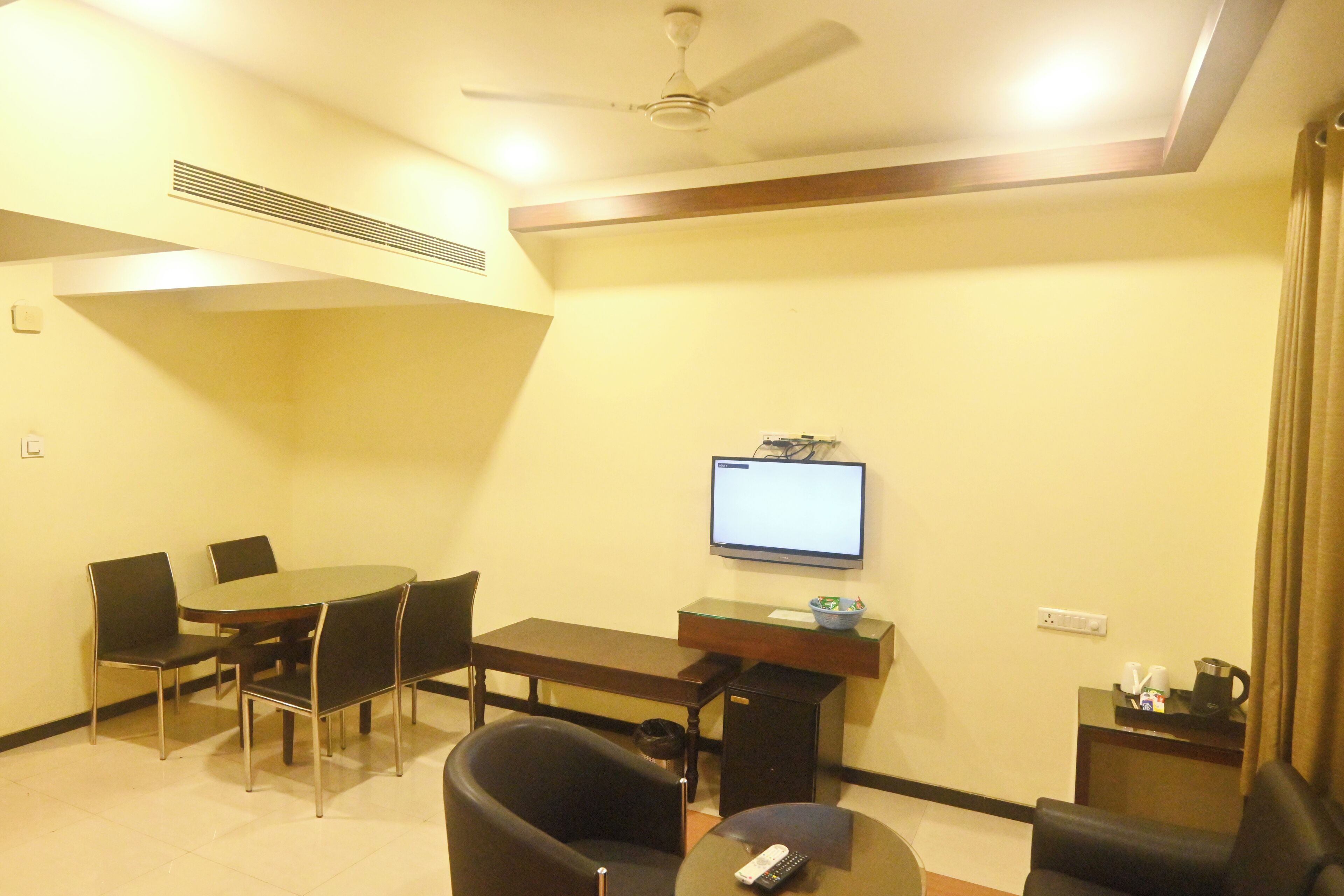A conference room with a table, chairs, a TV, and a coffee station.