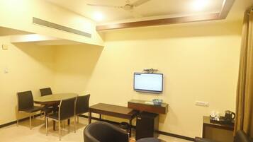A conference room with a table, chairs, a TV, and a coffee station.