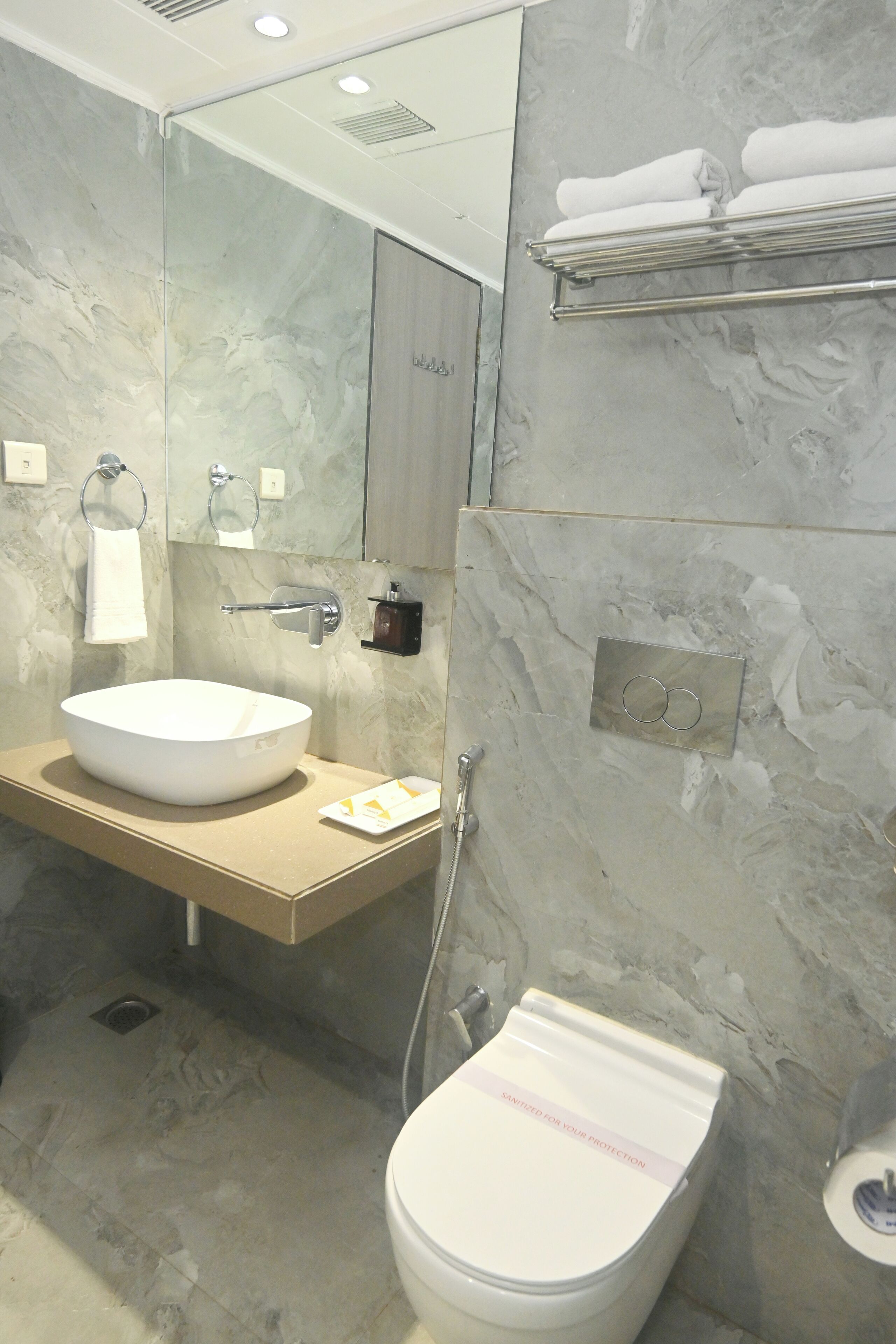 Un baño moderno con un lavamanos grande de mármol, un inodoro y un perchero para toallas.