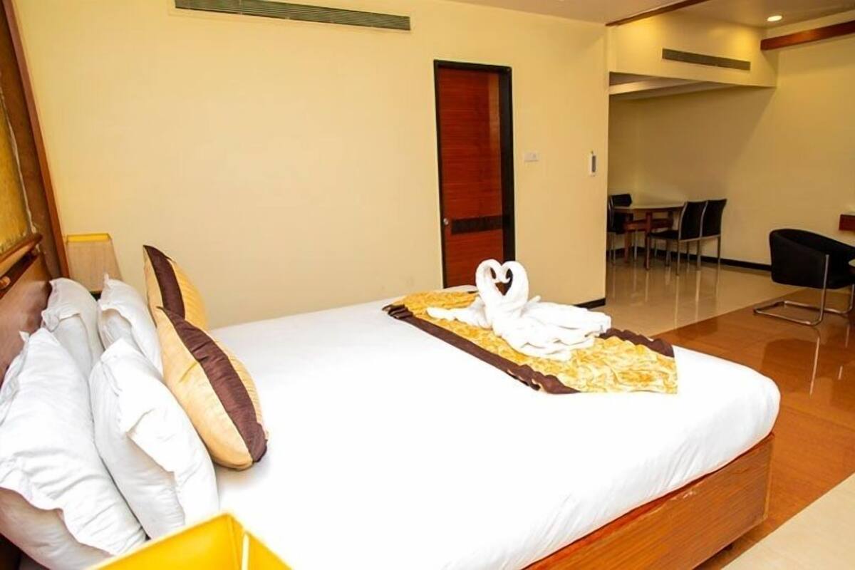 A hotel room with a bed, pillows, a tray with towels, a desk, and a chair.