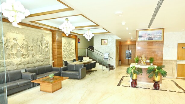 A spacious lobby with a marble floor, leather sofas, a wooden coffee table, and a reception desk with potted plants. - Hotel Simran Heritage (Raipur)