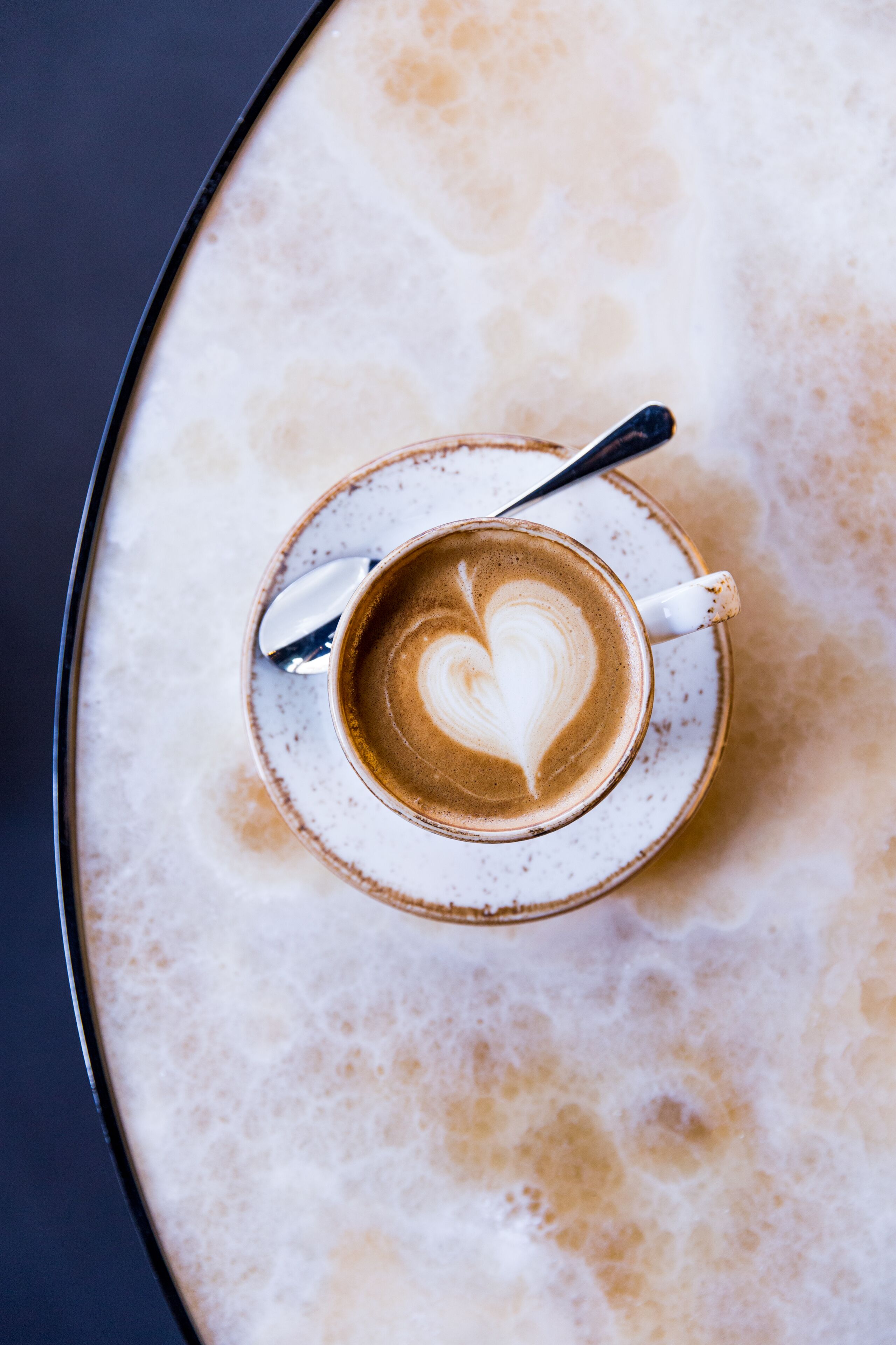 Eine Tasse Kaffee mit herzförmiger Kaffeezeichnung auf einem Untertasse.