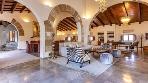 A spacious living area with high ceilings, stone arches, and a chandelier. - Palacio Can Marqués (Palma de Mallorca)