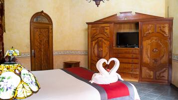 Una habitación de hotel con cama, televisor, mueble de madera y candelabro.