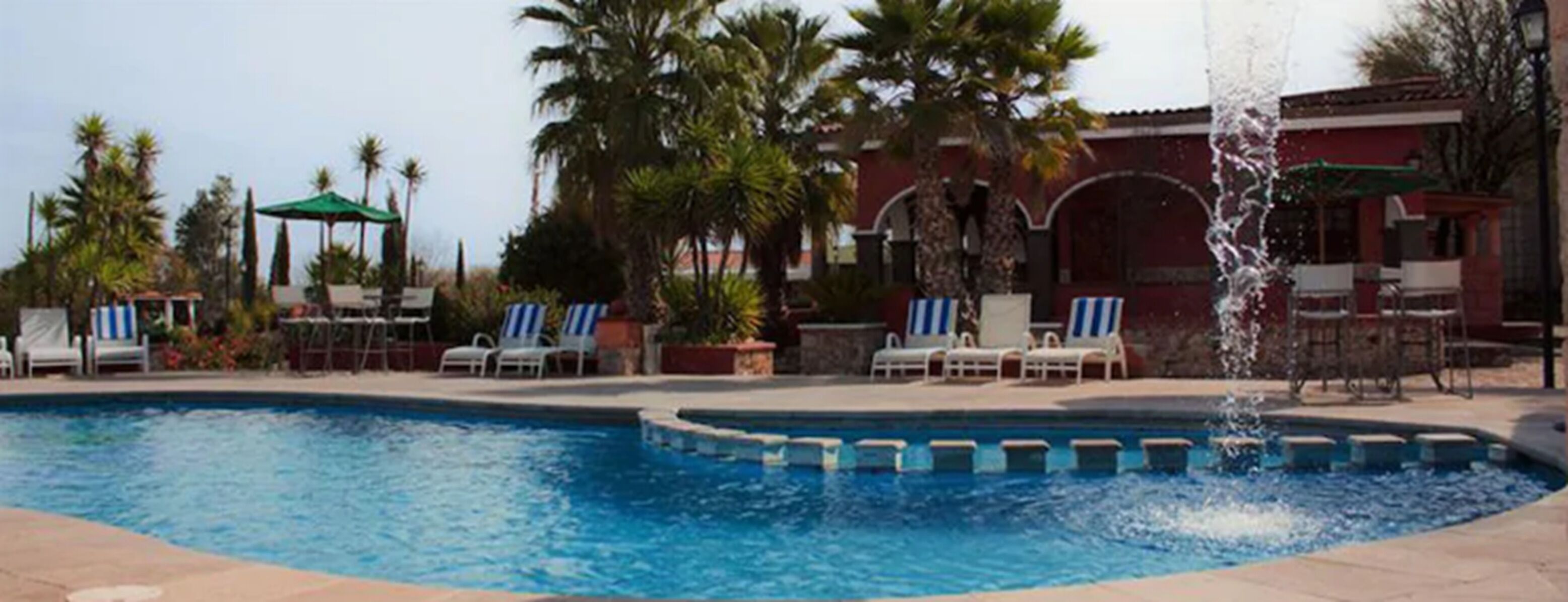 Una piscina con tumbonas y palmeras.