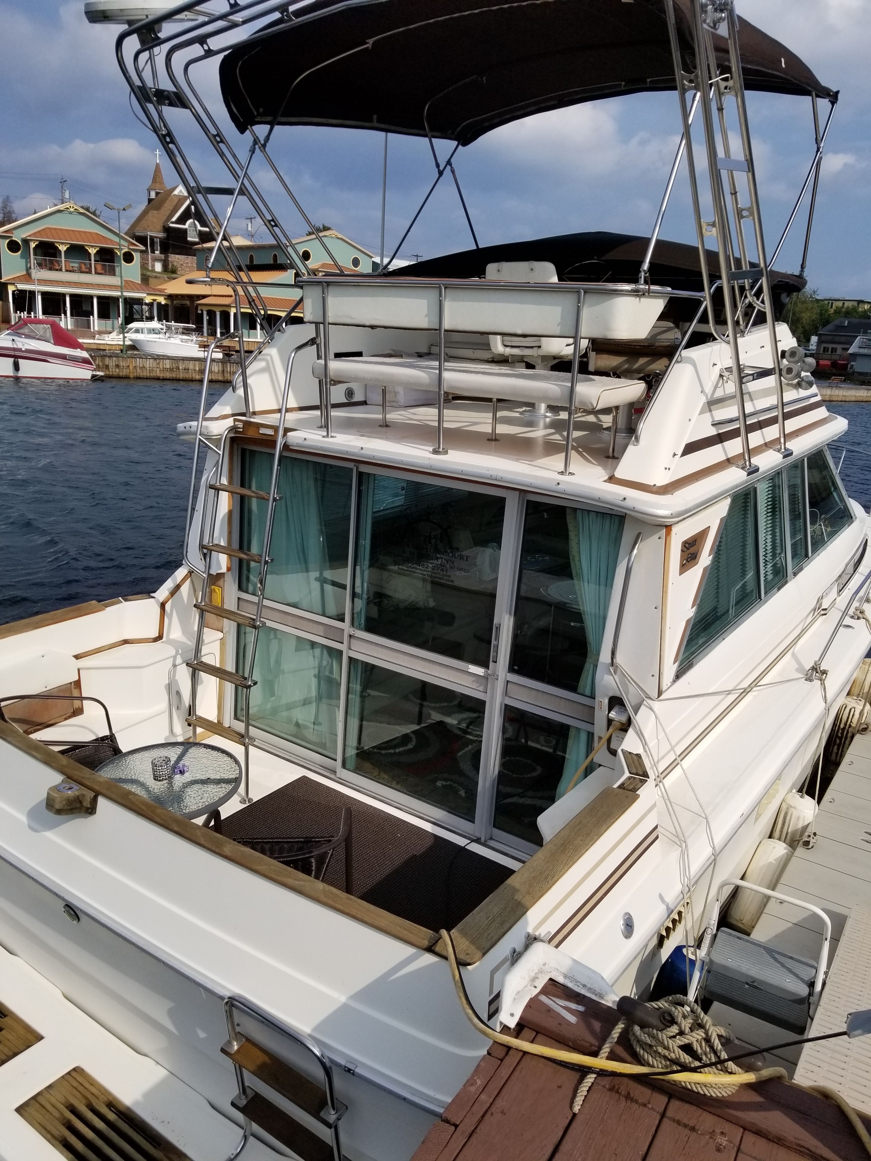 A boat with a covered deck area, a table with chairs, and a window.