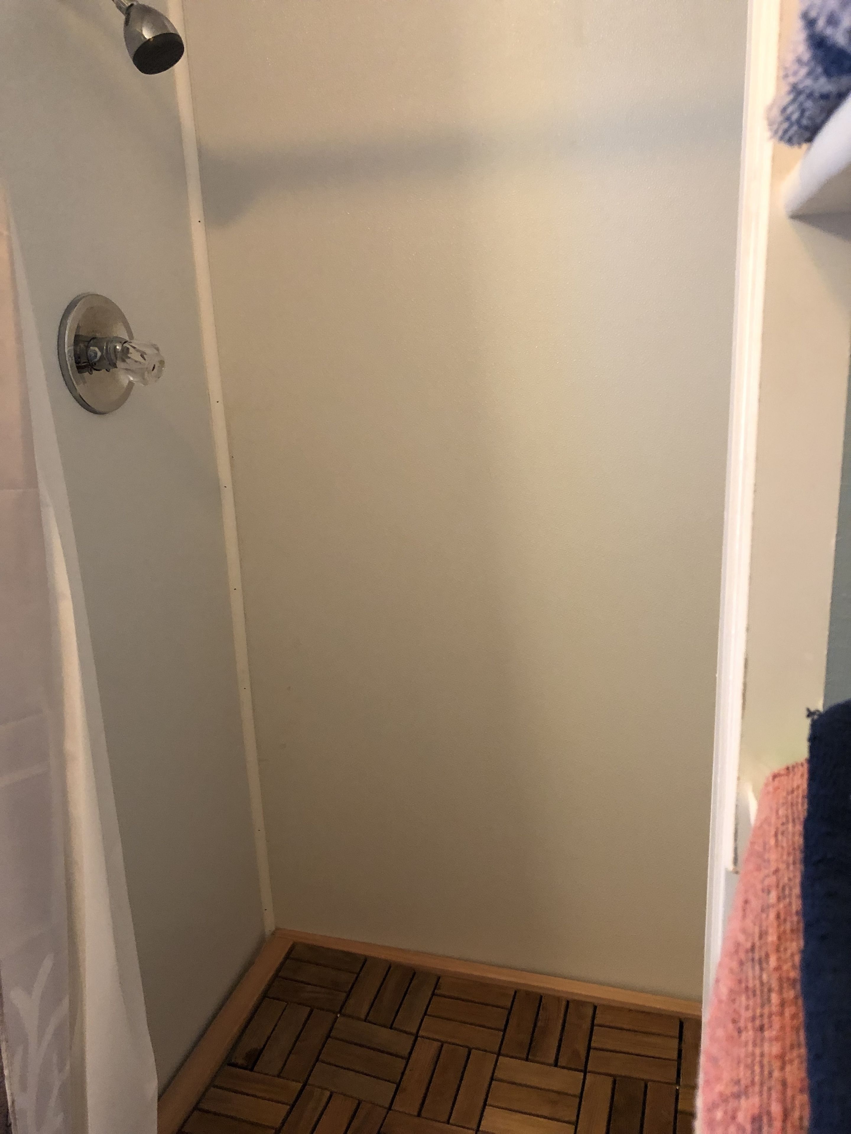Une salle de bain avec une douche, un porte-serviettes et un plancher en bois.