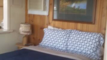 Un dormitorio con cama, ventana, cuadro y lámpara.