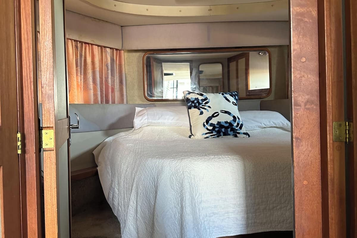 Een slaapkamer met een bed, een dressoir en een spiegel.