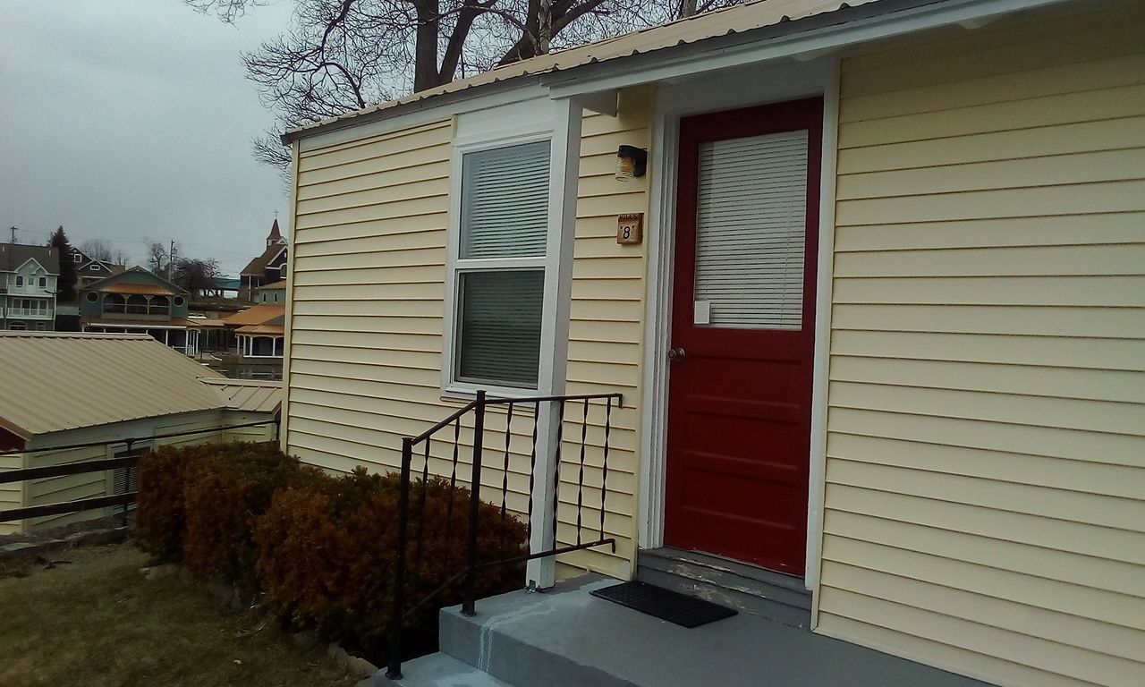 A single-story building with a red door and a small porch area.