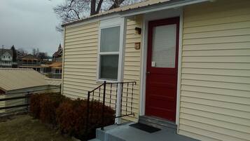 A single-story building with a red door and a small porch area.