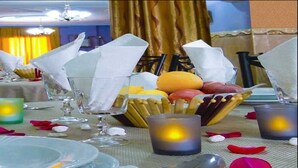 A dining table set with plates, glasses, and a bowl of fruit.