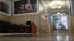 A lobby with a marble floor, a reception desk, a seating area, and wall art.