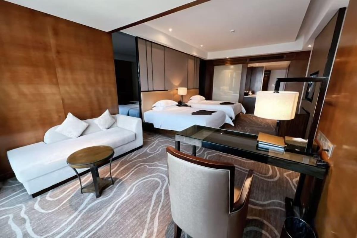 A hotel room with a sofa, a bed, a desk, and a chair.