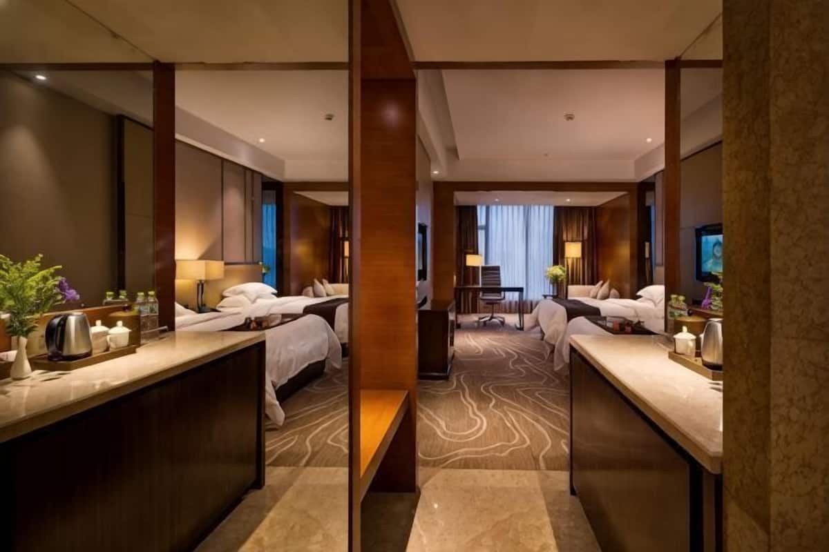 Habitación de hotel con una zona de estar central, dos camas, un escritorio y un televisor.