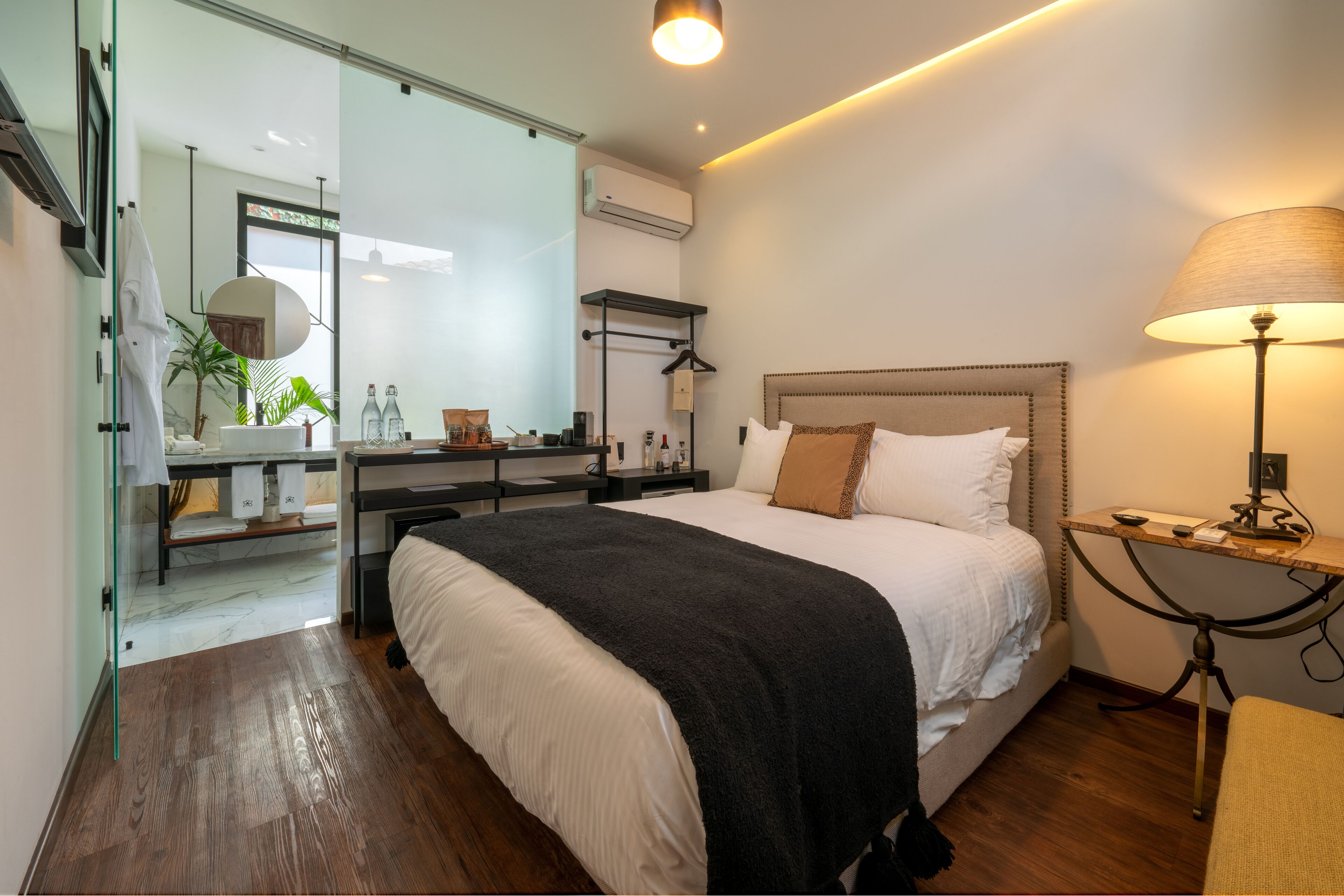 Moderni hotellihuone, jossa on suuri sänky, yöpöytä, lamppu ja peili.