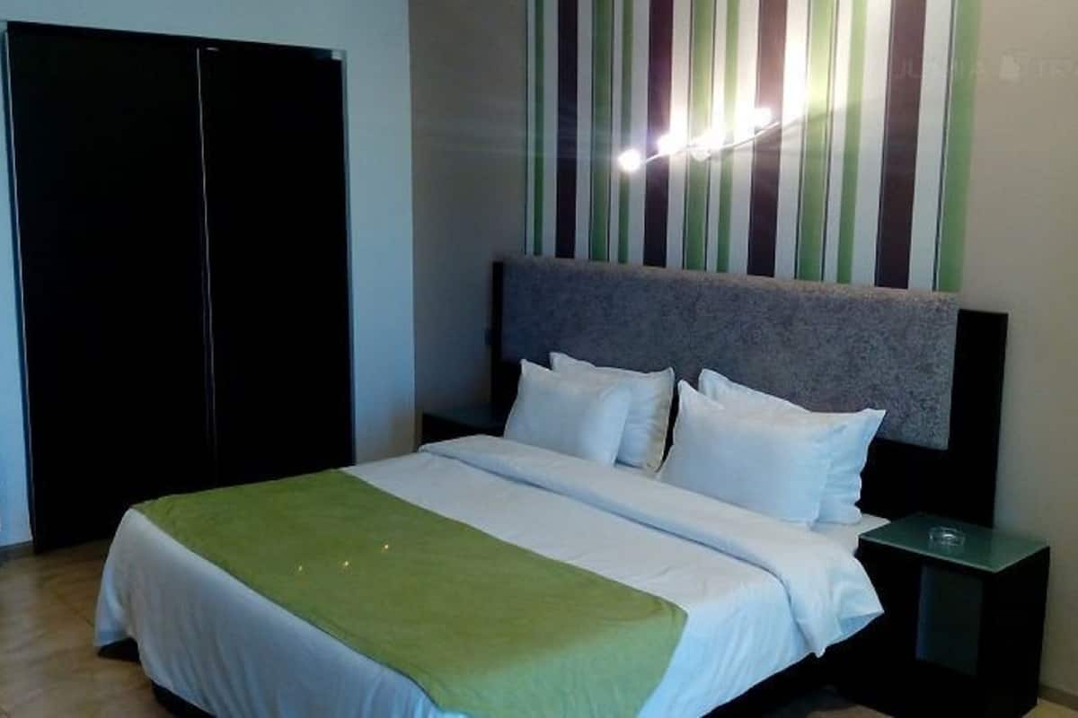 A hotel room with a bed, a nightstand, a wardrobe, and a striped wall.