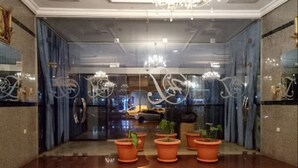 Un vestíbulo con piso reflectante, una araña y plantas en macetas.