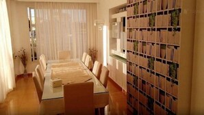 Un salón de conferencias con una mesa larga, sillas y una estantería con archivadores.