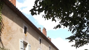 A rustic building with a stone entrance, a small garden, and a bench. - Domaine de Lalat (Montemboeuf)