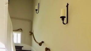 A staircase with a white balustrade, a wall-mounted candle holder, and a rope tied to the balustrade. - Domaine de Lalat (Montemboeuf)