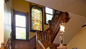 A wooden staircase with a handrail and a statue at the top. - Beaufort House Inn (Asheville)